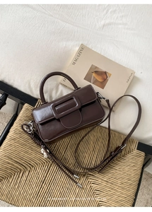 Macro detail of dark brown retro leather handbag with matte square buckle and strap