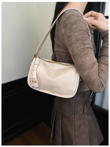 Detail shot of cream white PU leather shoulder bag with gold zipper and embossed logo