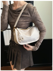 Detail view of beige leather shoulder bag with MUSE & GATS logo and fringe tassel