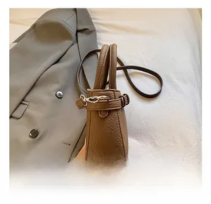 Detail shot of a brown pebbled leather bucket bag with silver hardware and strap