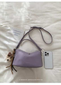 Close-up of purple minimalist underarm bag with silver buckle and cute bear charm