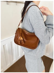 Detail showing the brown vintage shoulder bag with fringe tassel and gold rivet accents
