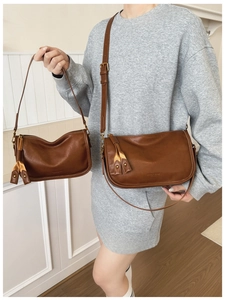Macro detail of dark brown leather texture and vintage gold hardware on crossbody bag