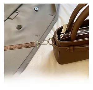 Detail view of high-quality silver metal hook and zipper on dark brown leather bucket bag