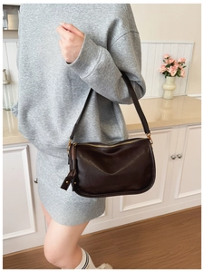 Close-up of retro chocolate brown shoulder bag with gold zipper and adjustable strap detail