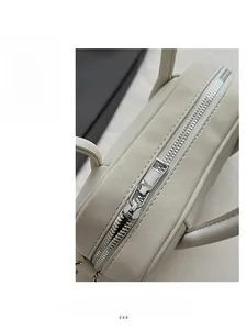 Dettaglio della cerniera in metallo argento e della pelle beige testurizzata della borsa