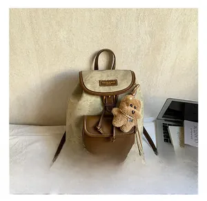 Detail of vintage canvas backpack with faux leather trim and a cute plush bear charm