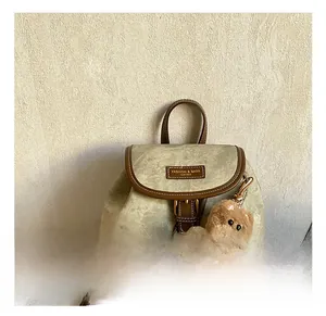 Close-up of retro backpack leather handle and metal buckle with cute plush bear charm