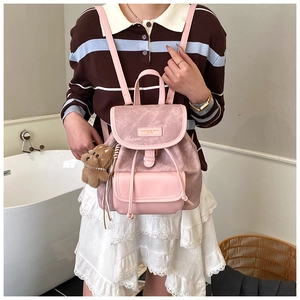 Detail of pink mini backpack with drawstring closure and brown plush bear charm accessory