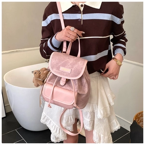 Detailed shot of pink drawstring backpack with flap closure and cute bear plush charm
