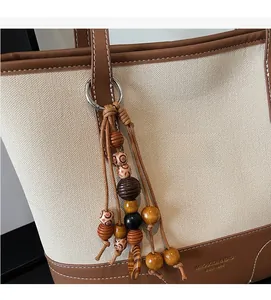 Detail van canvas draagtas met bruine lederen bies en houten kralen kwastje hanger