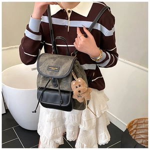 Detail view of retro canvas backpack with leather patchwork and a cute bear charm