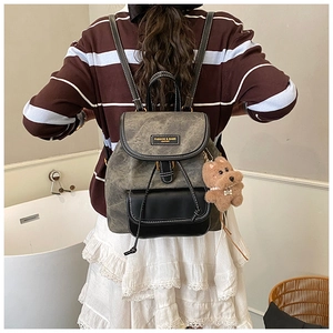 Model wearing a vintage canvas backpack in grey and black with a plush bear charm