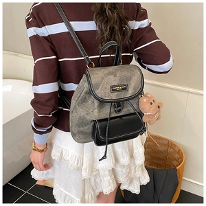 Detail of vintage gray backpack with faux leather trim and a cute plush dog charm accessory