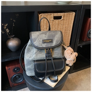 Close-up of vintage dark gray fabric backpack with leather details and bear pendant