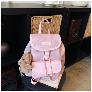 Detail of light pink leather backpack with metallic buckle, drawstring, and cute bear charm