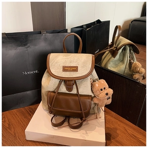 Detail view of vintage canvas backpack with brown leather trim and cute puppy pendant