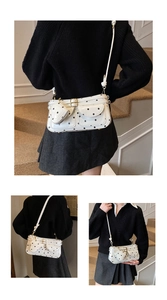 Close-up of white polka dot shoulder bag featuring heart charm and front pocket details