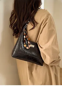 Détail du sac matelassé noir avec chaîne argentée et breloque en perles colorées