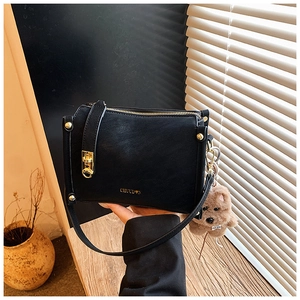Detailaufnahme der schwarzen Ledertasche mit goldenen Beschlägen und braunem Plüsch-Hund