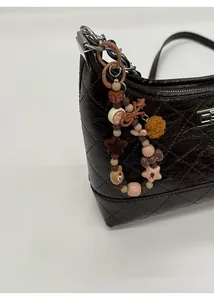 Vue détaillée du sac matelassé marron foncé avec breloques décoratives en perles et étoiles
