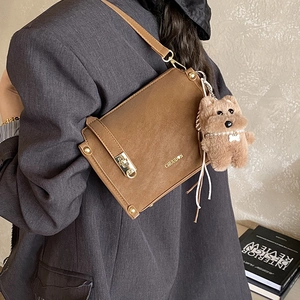 Detailansicht der Vintage-Umhängetasche in Braun mit Metallschnalle und Bär-Anhänger