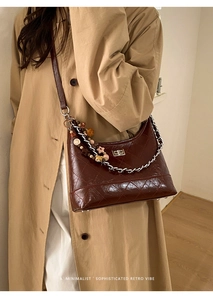 Détail du sac matelassé marron foncé avec chaîne argentée et breloques sur le côté