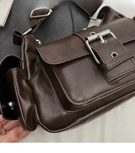 Detail of vintage coffee brown PU leather bag with large front pocket and metal rivets