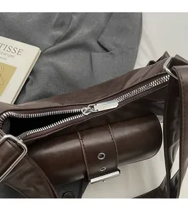 Close-up of a smooth silver zipper head on a vintage brown leather crossbody bag