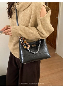 Détail du sac à bandoulière en cuir noir matelassé avec chaîne argentée et breloque