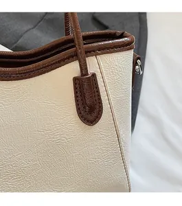 Primer plano de bolso cubo retro crema con bordes marrones y costuras detalladas