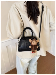 Dettaglio di una borsa a cuscino nera semicircolare con ciondolo a orso e logo LUKADI