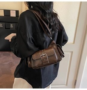 Detail view of brown vintage motorcycle bag with silver metallic buckle on a model