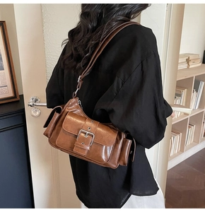 Detail of vintage brown shoulder bag with large silver buckles and utility side pockets