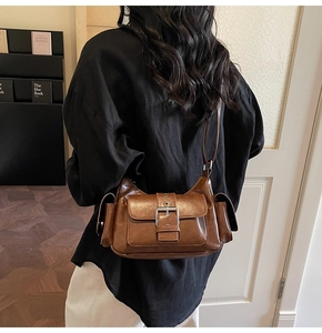 Detailed view of vintage brown crossbody bag with metal buckles and side flap pockets