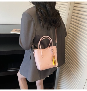 Detalle de bolso de cuero rosa con cuentas de colores llevado por modelo en traje gris