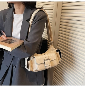 Detail of a beige multi-pocket shoulder bag featuring silver buckles on a professional model