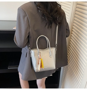Detalle de bolso plateado metalizado con adorno de cuentas de madera y correa larga