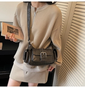 Detail of vintage textured leather crossbody bag with multiple utility pockets and buckles