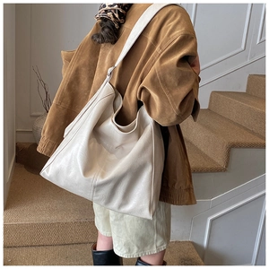 Detail view of the large off-white hobo bag with smooth texture and wide strap