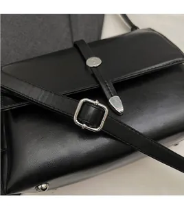 Detail of black leather shoulder bag with adjustable silver buckle strap on blazer