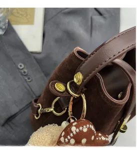 Gros plan d'un sac en daim marron avec ferrures dorées et breloques décoratives de style rétro