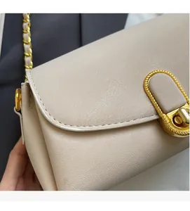 Détail du sac en cuir blanc crème avec fermoir doré et texture en cuir litchi grainé