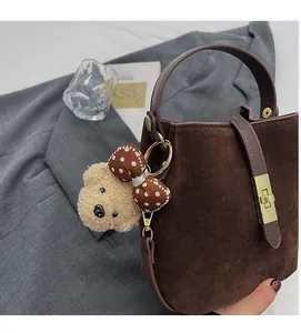Détail du sac seau marron foncé mat avec boucle dorée et charm de petit ours peluche
