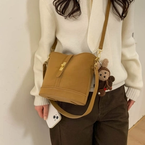 Model showing a vintage ginger yellow bucket bag with a cute plush bear charm