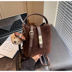 Détail d'un sac seau vintage marron mat avec fermoir doré et breloque petit ours