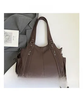 Detail of dark brown lychee leather tote bag with dual zippers and side pockets