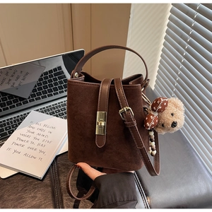 Détail du sac seau vintage marron foncé en suédine avec pendentif ours et fermoir doré