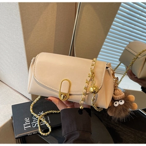 Détail du sac oreiller crème avec fermoir en U doré, chaîne en métal et breloque en peluche