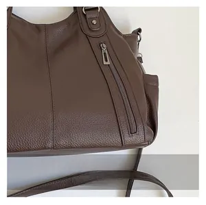 Detail view of coffee leather tote bag showing vertical zipper and stitching craft